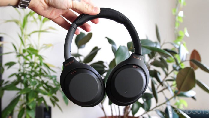 Prime Day slashes the Sony WH-1000XM4 price to less than A photo of the Sony WH 1000XM4 noise cancelling headphones held by a man in front of indoor plants.