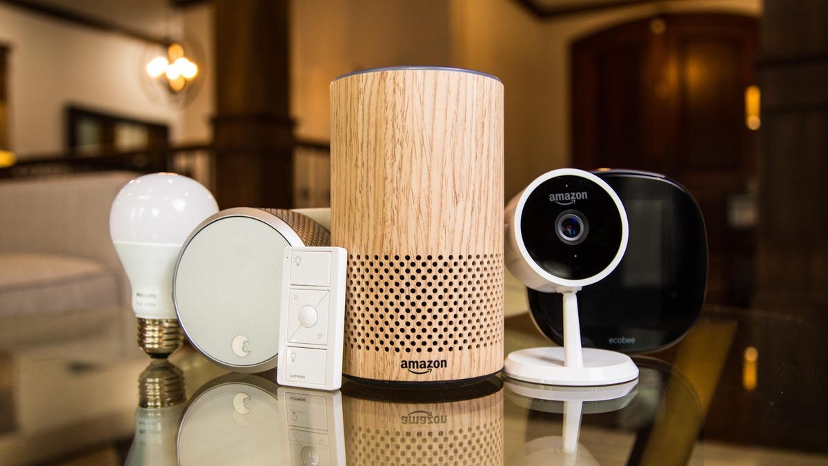 An array of smart home devices sit on a glass countertop. 