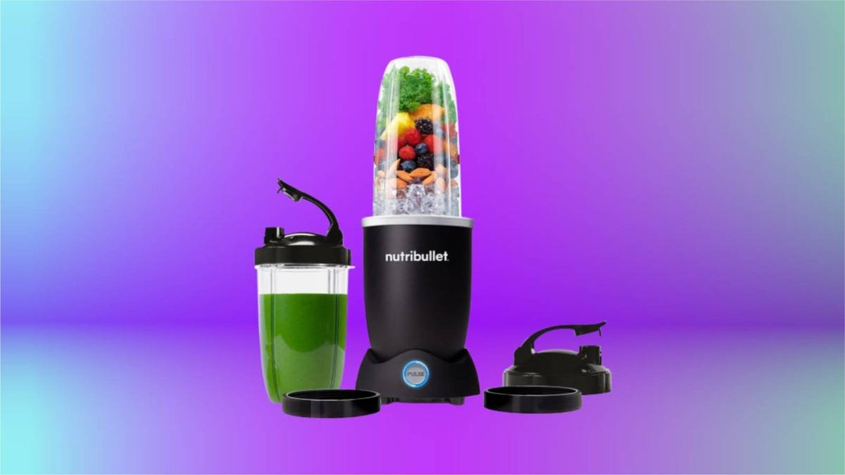 Image shows a Nutribullet blender with ingredients layered inside next to an already pureed green smoothie in a Nutribullet to-go container as well as the lid accessories, all displayed against a gradient purple-blue background