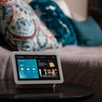 A google nest hub smart display on a bedside table.