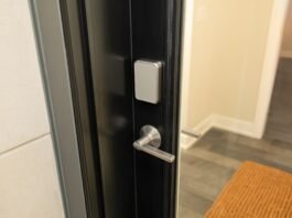 A silver door lock on a black door above a silver handle