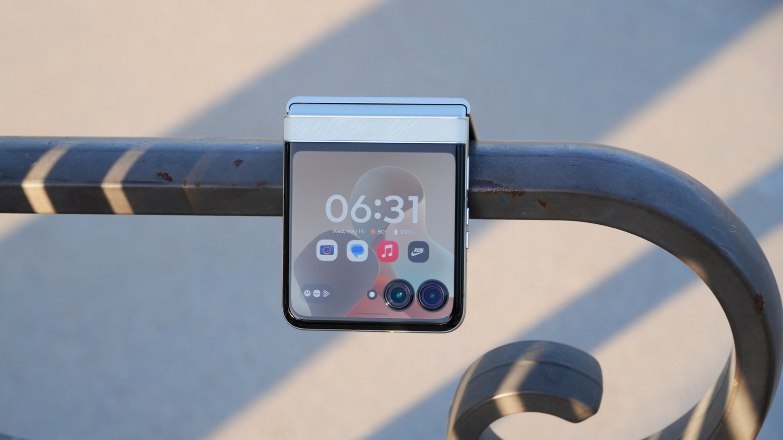 The Motorola Razr 2025 in the Pantone Lightest Sky colorway hanging from a park bench.