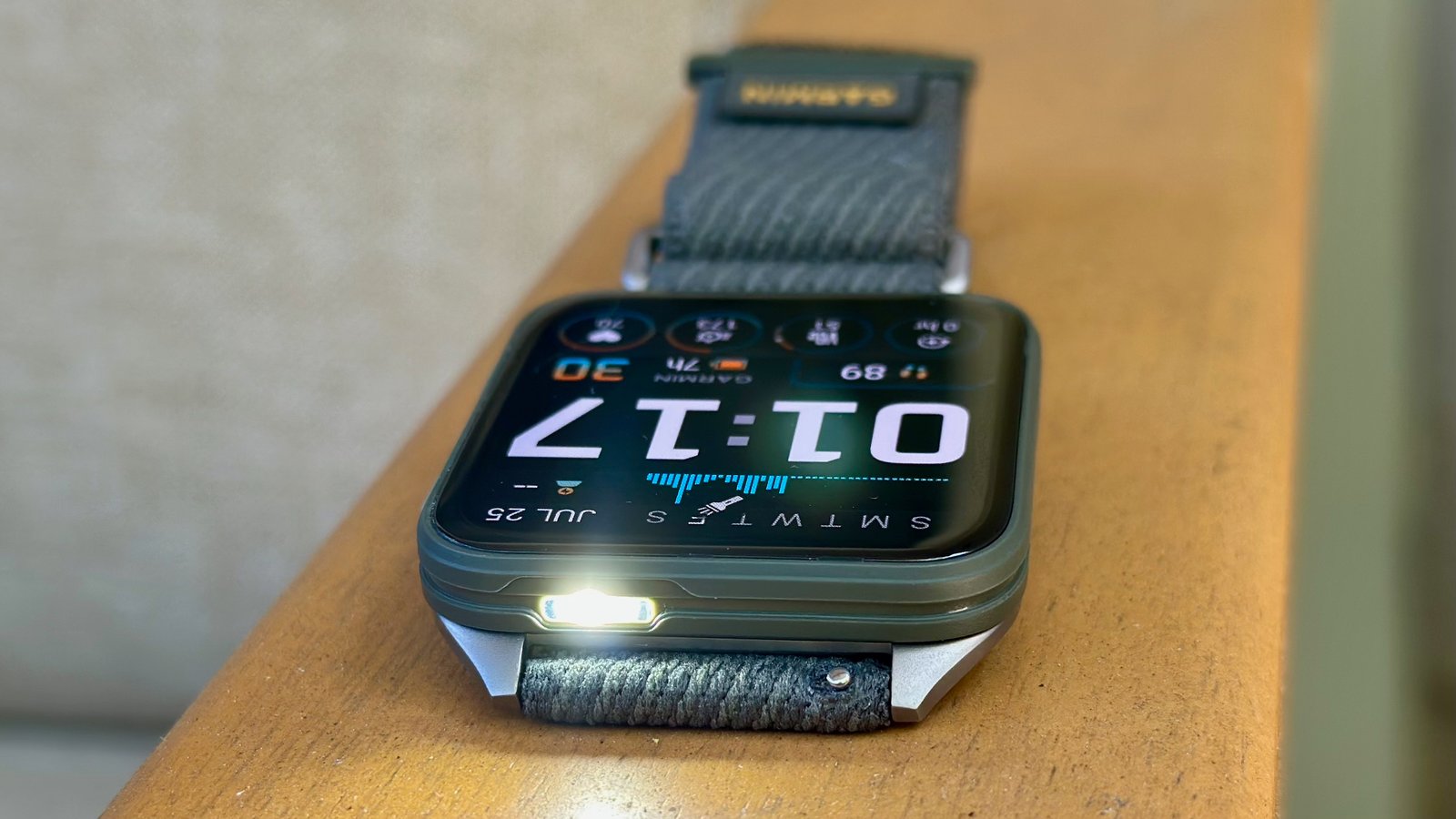 The Garmin Venu X1 sitting on an armrest, pointed toward the camera with the flashlight on.