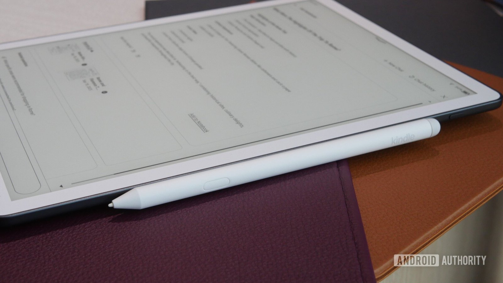 A Kindle Scribe Colorsoft rests ona surface along with its Premium Stylus.