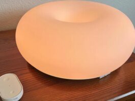 Ikea smart lamp glowing orange on a table.