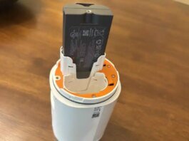 A Ring spotlight camera showing its battery slots with a battery halfway out.