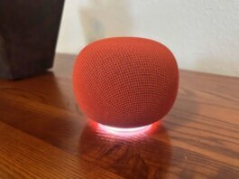 A red Google speaker on a wood table.